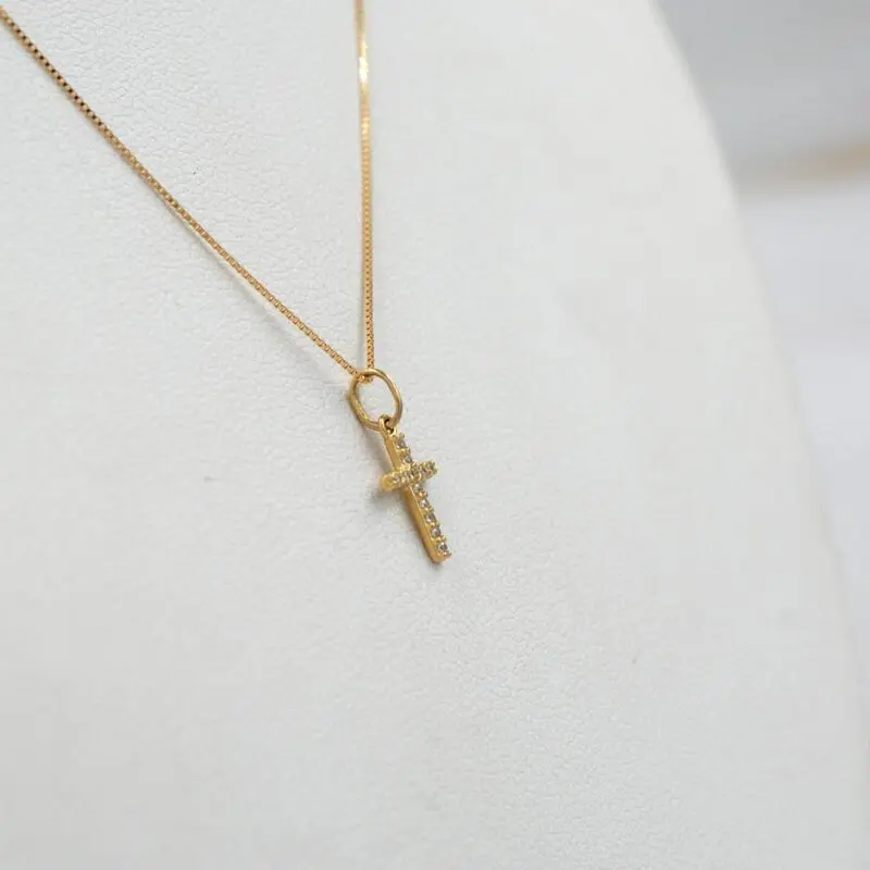 onjunto de joyería fina en oro 18k con colgante cruz brillante.