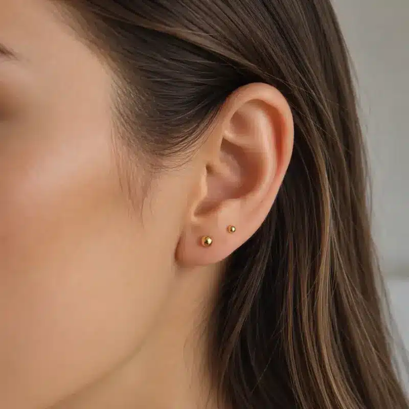 Abridores Bolita de Oro Amarillo 18K puestos en la oreja de una modelo